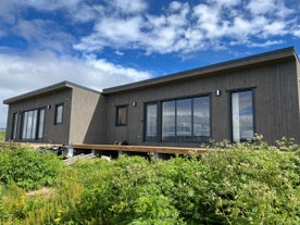 Close-up exterior view of the modern Eyri Seaside Houses in Northwest Iceland with greenery in front of the house.