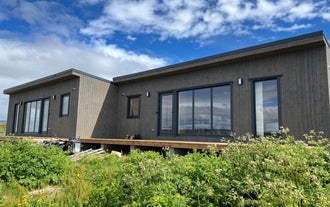 Close-up exterior view of the modern Eyri Seaside Houses in Northwest Iceland with greenery in front of the house.