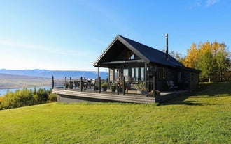 Luksuriøs sort hytte nær Akureyri med udsigt over Eyjafjordur-fjorden under en klar himmel.