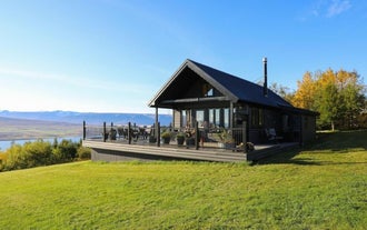 Luxurious black cabin near Akureyri overlooking Eyjafjordur Fjord under a clear sky.