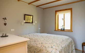 Hyggeligt soveværelse med blomstrede sengetekstiler i Heidarsel Cabin nær Akureyri.