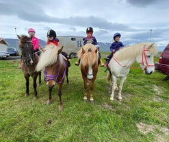 Children happily mount their horses in preparation for their horseback riding tour.