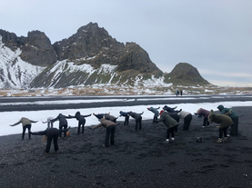 Probeer eenvoudige yogahoudingen op het zwarte zand van de baai van Hofn.