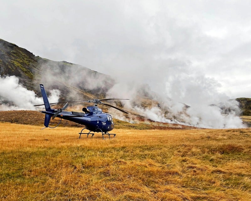 Hot steam rises from the surface as a helicopter lands nearby.