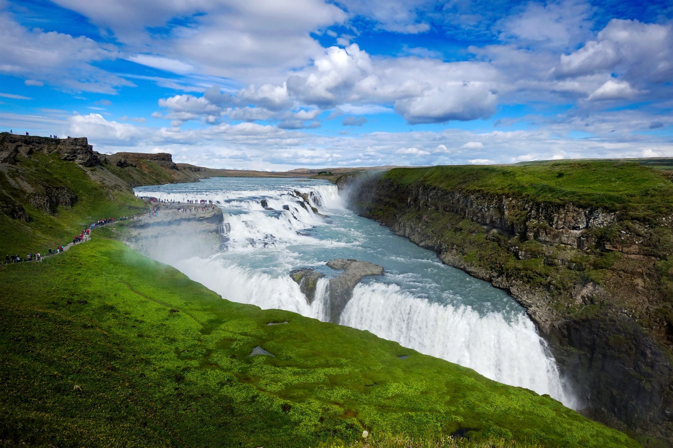 Gullfoss waterfall surrounded by lush greenery during summer in Iceland.