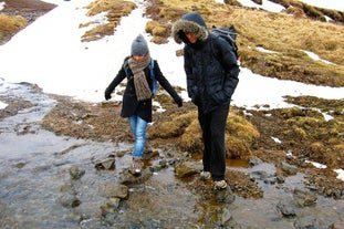 游客在Reykjadalur的私人徒步旅行中穿越一条河流。