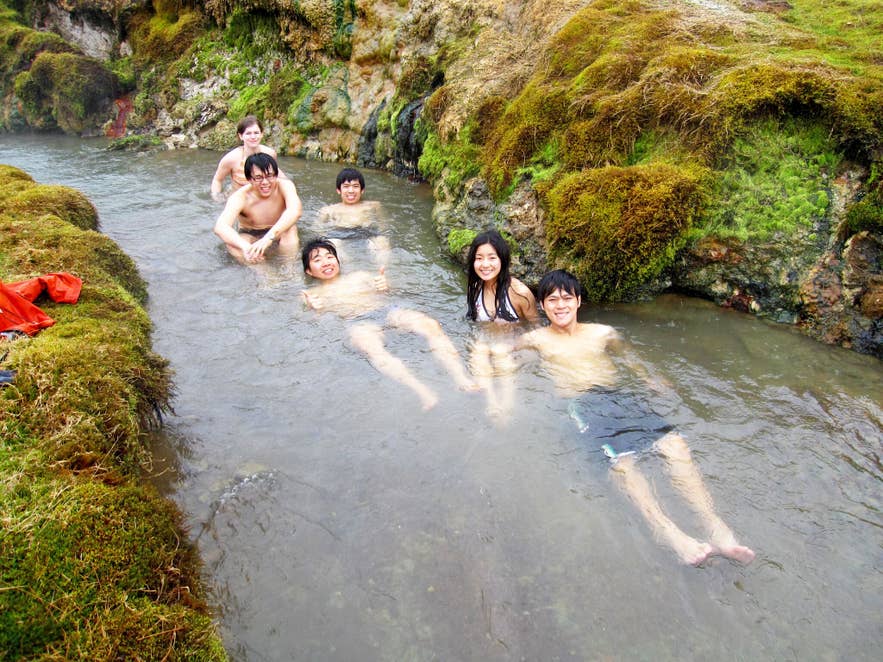 Eine kleine Gruppe von Touristen badet im warmen geothermischen Fluss von Reykjadalur.