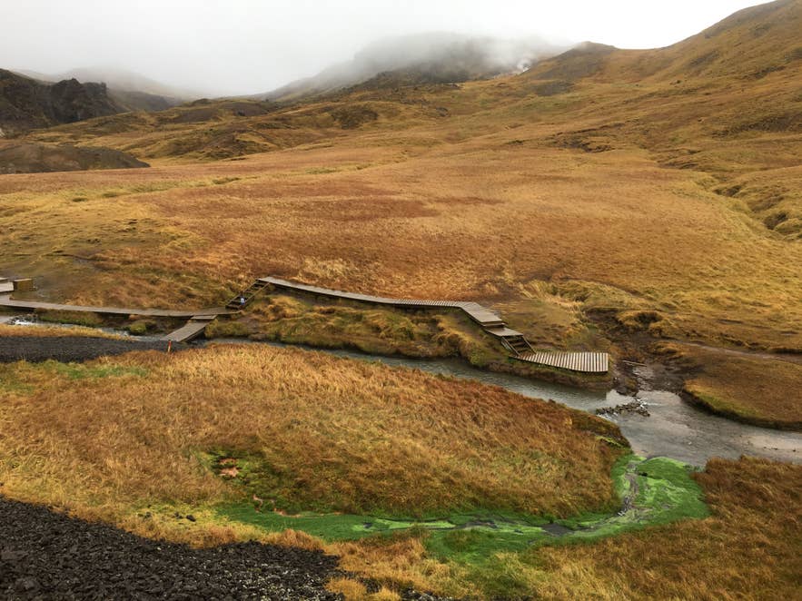 Blick von oben auf den Holzsteg im Reykjadalur-Tal am warmen Fluss