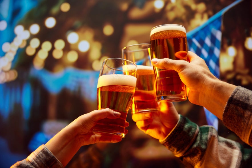 A group of travelers in Reykjavik, Iceland cheer with mugs of beer during a shared moment.