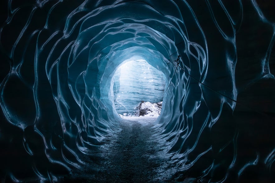 The inside of an ice cave beneath the Katla Glacier Volcano shows shimmering icy walls, shaped by centuries of volcanic and glacial activity.