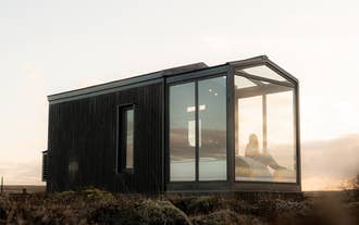 Woman relaxing inside the Tiny Glass Lodge at sunrise