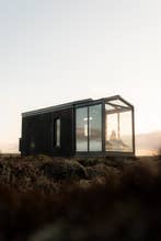ผู้หญิงพักผ่อนใน Tiny Glass Lodge ยามพระอาทิตย์ขึ้น
