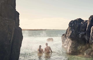 Due visitatori si godono un rilassante bagno nella laguna ammirando il vasto oceano.