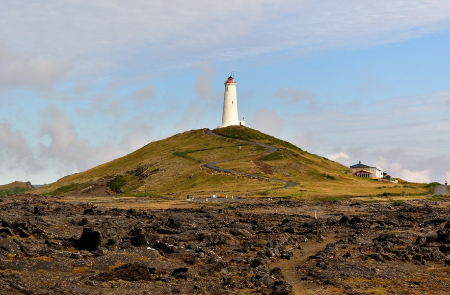 White Reykjanesviti Lighthouse on a grassy hill surrounded by lava fields on the Reykjanes Peninsula.