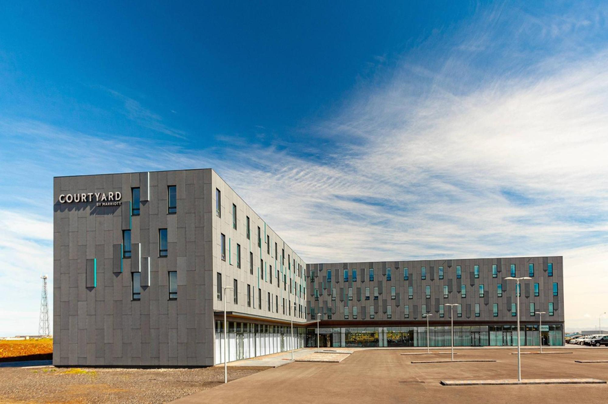 Exterior of Courtyard by Marriott hotel near Keflavik Airport, with modern architecture under a blue sky.