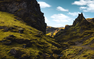 Rugged rock formations and green moss-covered cliffs in Thakgil Canyon, South Iceland.