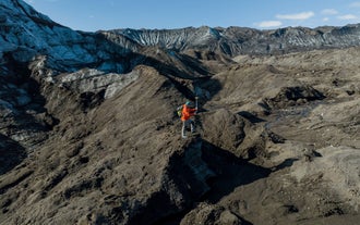 A researcher maps ice formations during the Ice Mapping Expedition at Katla Glacier in Katla Geopark on a clear summer day.