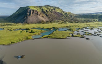 Aerial view of mossy highland terrain and volcanic hill near Vik, with glacial lakes and braided river patterns.