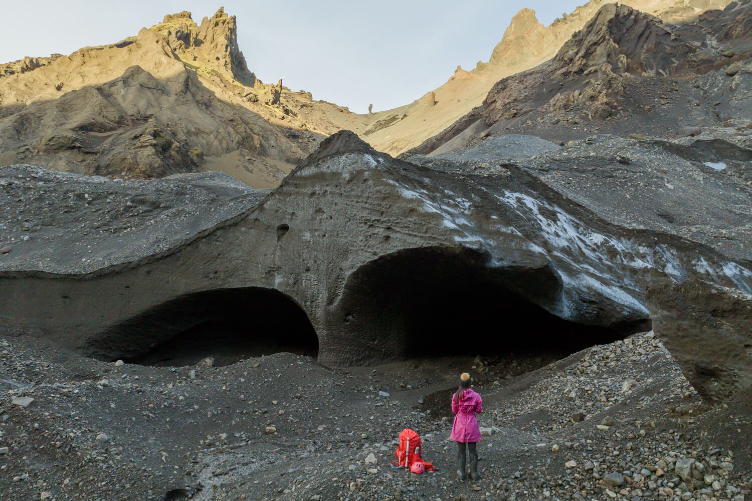 Hiker standing near Krossarjokull Glacier in Katla Geopark, with black volcanic sand.