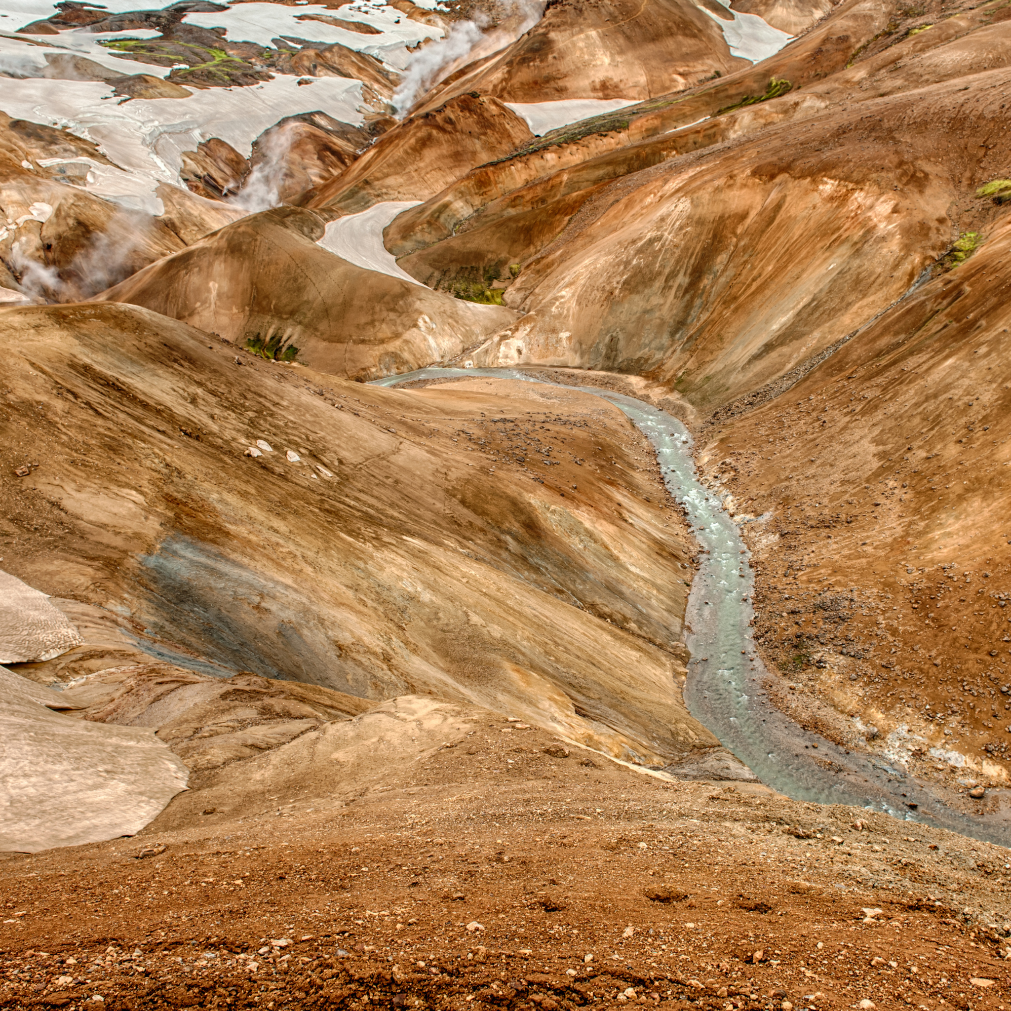 A steaming geothermal river winds through the colorful rhyolite hills of Hveradalir in Kerlingarfjoll, Iceland.