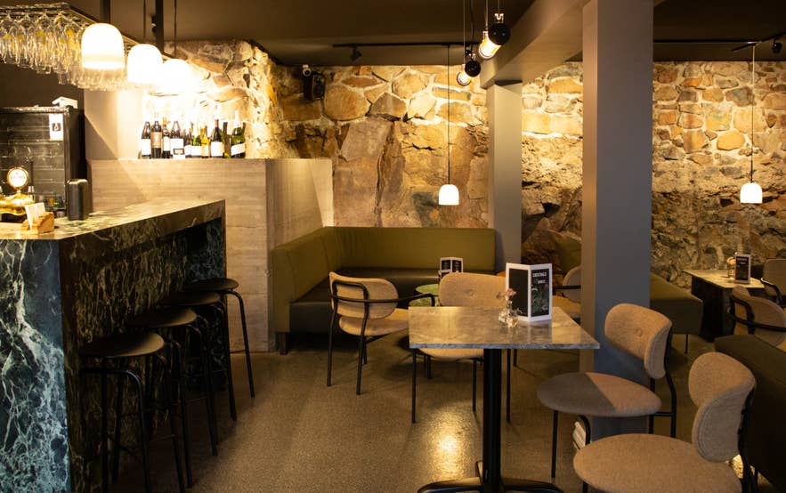 Narfeyrarstofa's cozy bar interior with a stone wall and warm lighting. Narfeyrarstofa's cozy bar interior with a stone wall and warm lighting.