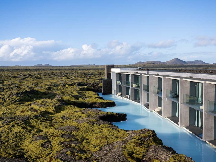 The Retreat Hotel at Blue Lagoon Iceland with luxury suites overlooking a private geothermal lagoon, surrounded by moss-covered lava fields and distant volcanic mountains.