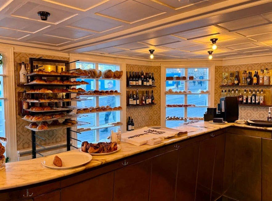 Intérieur de la boulangerie BakaBaka à Reykjavik, avec des étagères garnies de pâtisseries fraîches, de croissants, ainsi que de vin et de spiritueux, dans un décor chaleureux au style vintage.