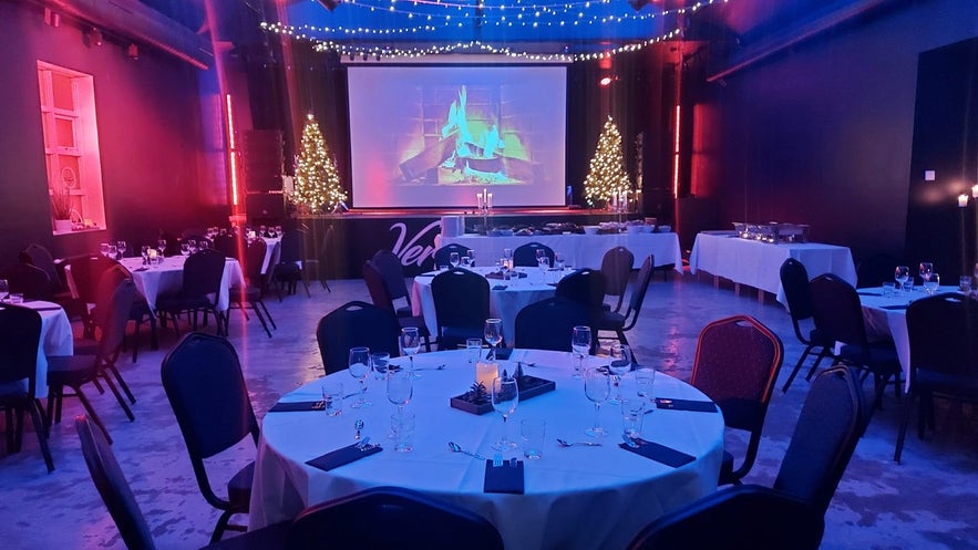 Elegant dining setup with candles and Christmas trees at Vitinn Mathus restaurant in Akureyri, Iceland.