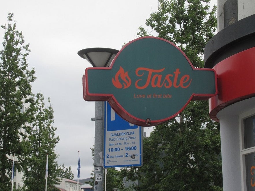 Outdoor sign of Taste Restaurant in Akureyri, inviting guests with a fun design and tasty promise.