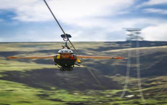 Persona con casco y arnés deslizándose en posición horizontal, como volando, en una tirolesa en el sur de Islandia.