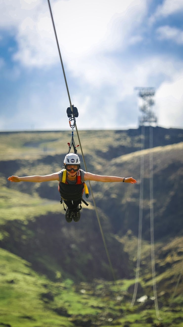 Rider wearing helmet and harness in a head-first ‘flying’ position as they zipline forward in South Iceland..