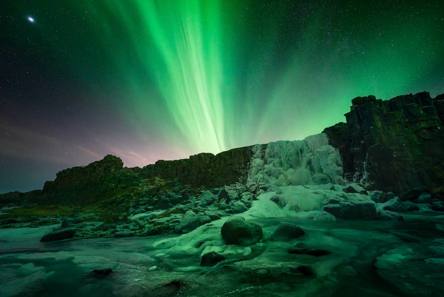 La cascata Oxararfoss ghiacciata sotto l'aurora boreale nel Parco Nazionale di Thingvellir, nel Circolo d'Oro islandese.