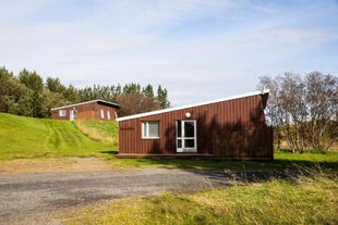 View of the front of the two cottages at Skalholt Cottages, surrounded by greenery.