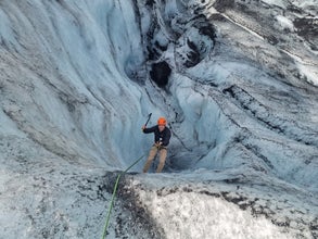 Ice climber scaling frozen wall on Solheimajokull Glacier.