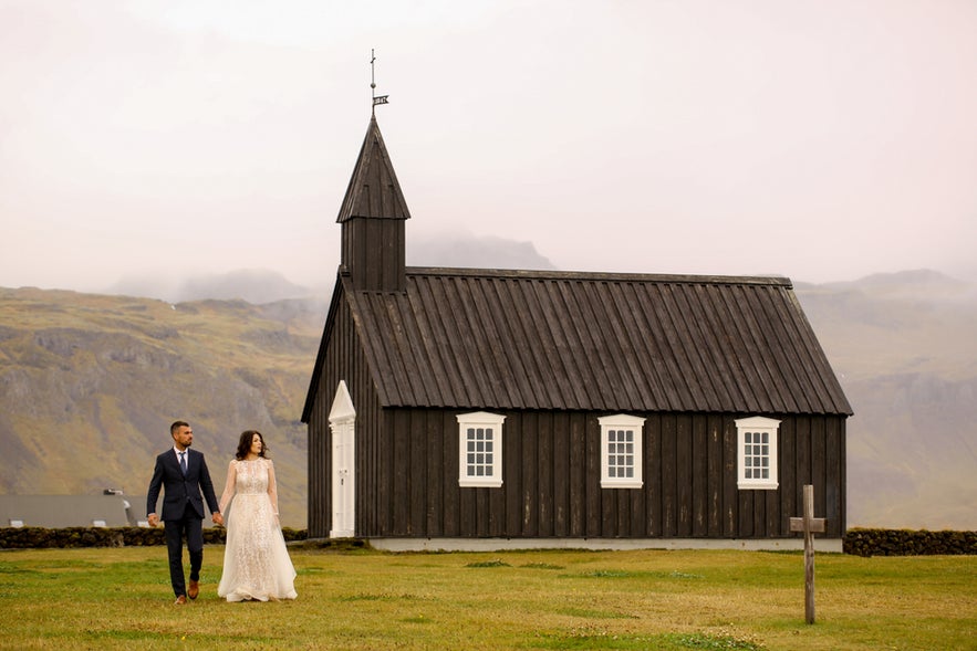 Couple poses in front of a historic black church, embodying timeless romance and charm.