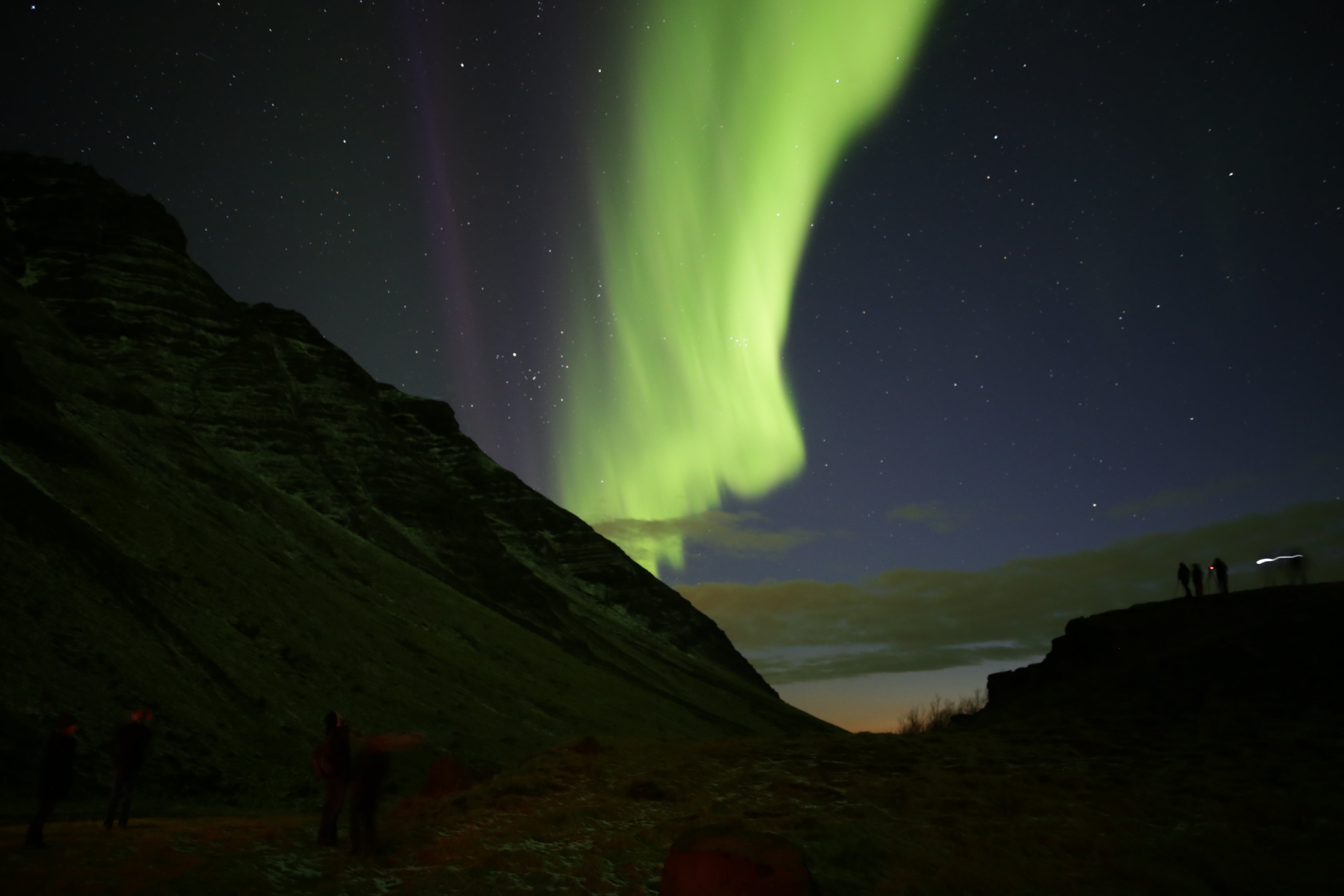 The aurora borealis lights up the starry night sky in a brilliant splash of green, a winter bucket list adventure for many travelers to Iceland.
