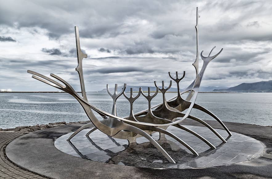 아이슬란드 레이캬비크에 위치한 ‘선 보이저(Sun Voyager)’ 조각상은 현대적인 스테인리스 스틸 디자인으로, 팍사플로이 만과 멀리 보이는 산들, 그리고 장엄한 구름 낀 하늘을 내려다보고 있다.