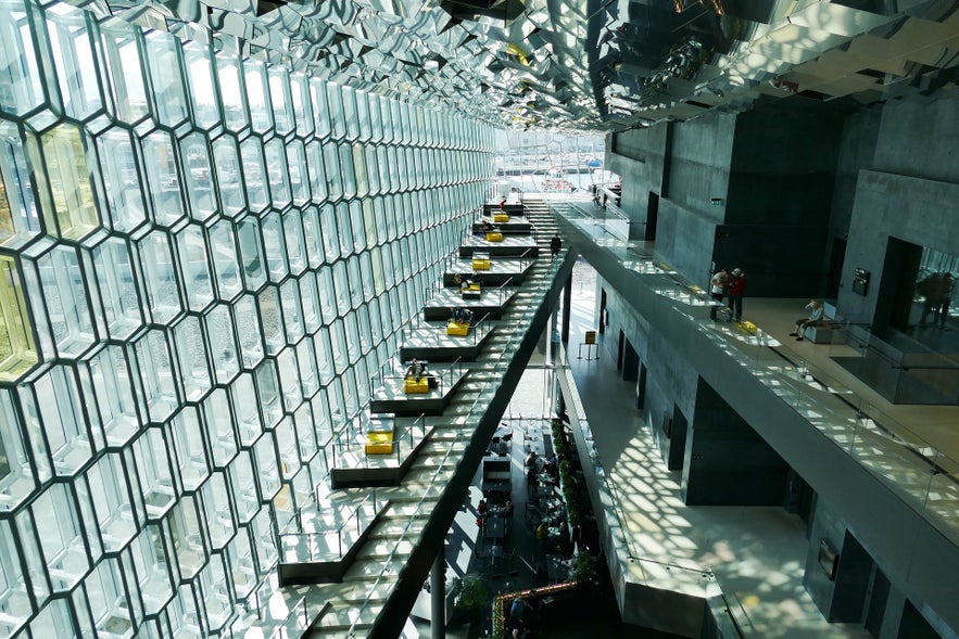 Interior of Harpa Concert Hall in Reykjavik, Iceland, with geometric glass facade, honeycomb windows, modern architecture, open walkways, and natural light.