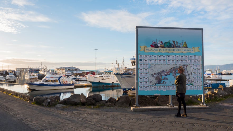 Reykjavik Old Harbour in Iceland with fishing boats, marina, harbor map sign, person reading map, calm water, and soft summer evening light.
