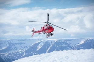 A helicopter about to land on a mountain peak for some heliskiing.