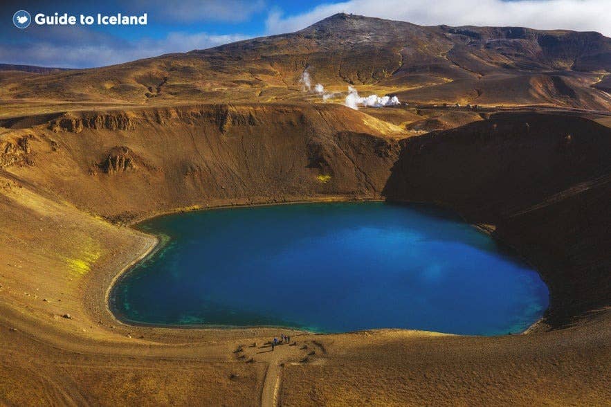 De Viti-krater in het vulkanische gebied Krafla in Noord-IJsland, met een helderblauw kratermeer omringd door ruig vulkanisch terrein en dampende geothermische bronnen.