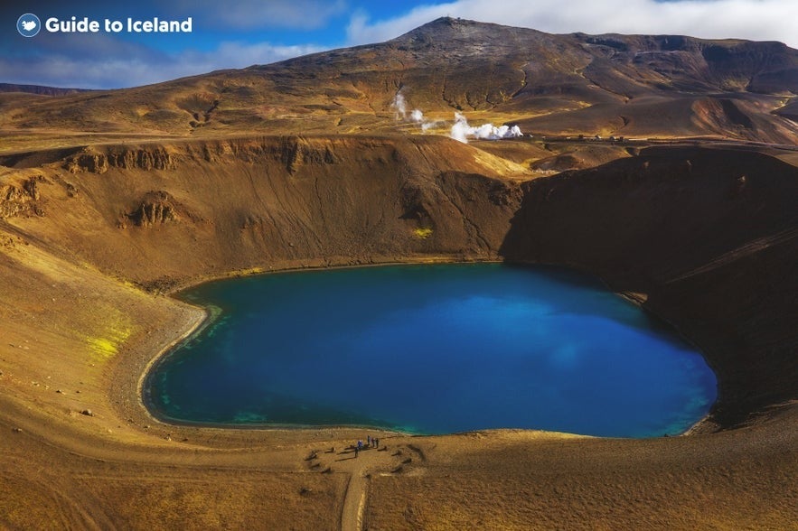 Viti crater in Krafla volcanic area, North Iceland, with vibrant blue crater lake surrounded by rugged volcanic terrain and steaming geothermal vents.
