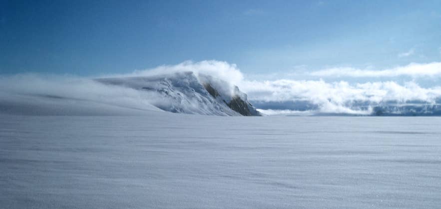 De met sneeuw en mist bedekte vulkaan Grimsvotn op de gletsjer Vatnajokull, de actiefste vulkaan van IJsland, onder een helderblauwe hemel.