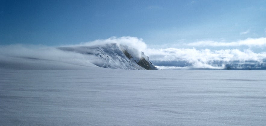 Grimsvotn volcano covered in snow and mist on Vatnajökull glacier, Iceland's most active volcano under clear blue sky.