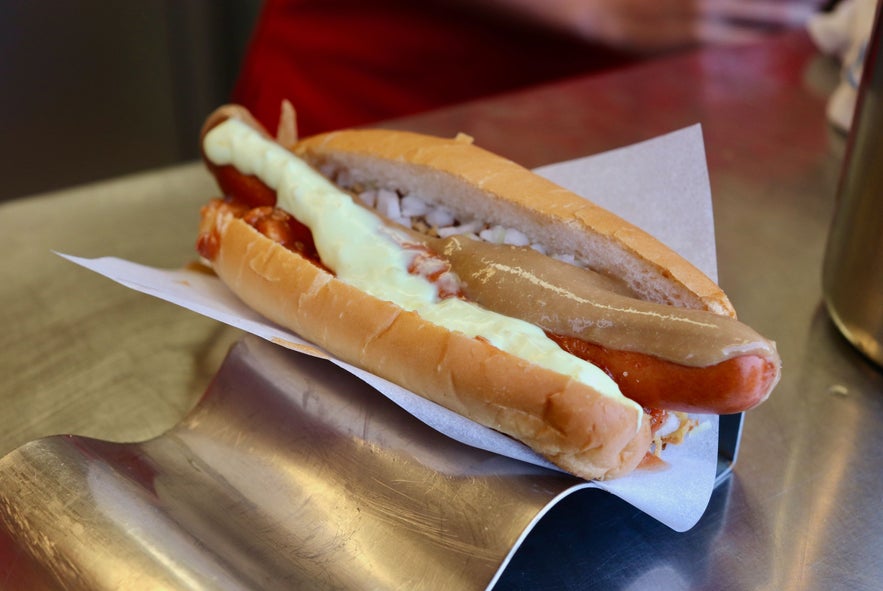 Traditional Icelandic hot dog with crispy bun, lamb-based sausage, remoulade, ketchup, and fried onions at Reykjavik street food stand.