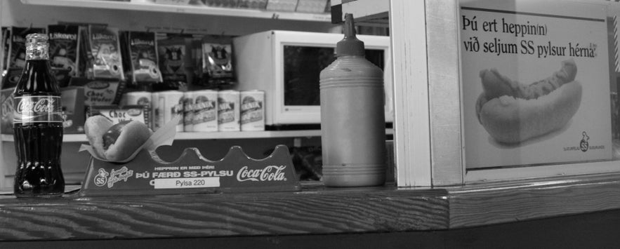 Vintage 2008 photo of an Icelandic hot dog with Coca-Cola inside a small shop, showing SS pylsur sign and local Icelandic snacks.