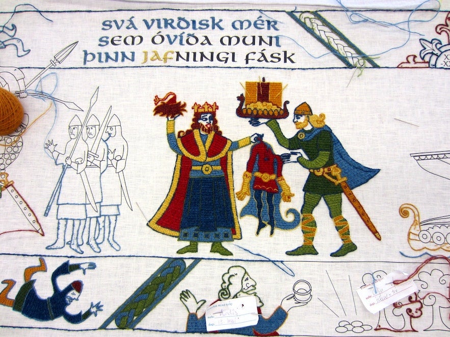 Medieval Icelandic saga scene embroidered in tapestry style, showing Norse figures, weapons, and Old Norse text.