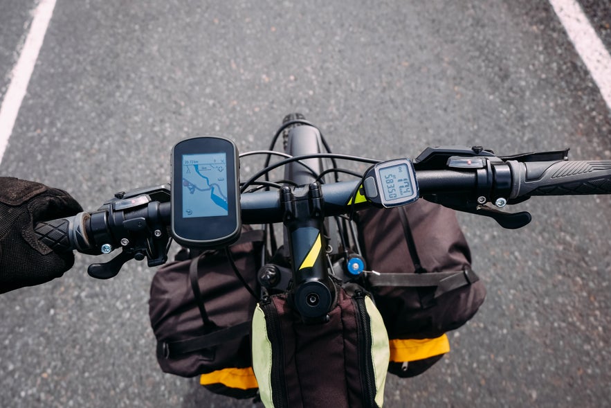 Handlebar view of a touring bike with GPS and gear bags on Iceland’s Route 1 in summer