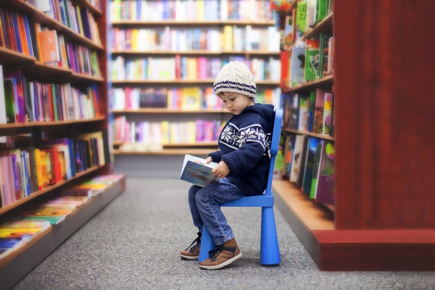 Adorable little boy, sitting in a book store, looking at books