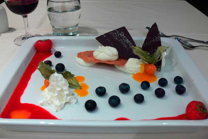 A dessert of skyr with blueberries, fresh fruit, and whipped cream served in a restaurant.